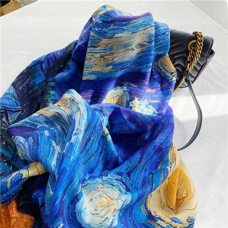 Close-up of a lightweight Starry Night wool wrap styled beside a black handbag, showing blue and gold artwork