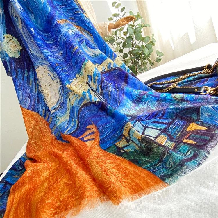 Blue printed wool scarf spread on white fabric, revealing orange fringe and detailed Starry Night artwork