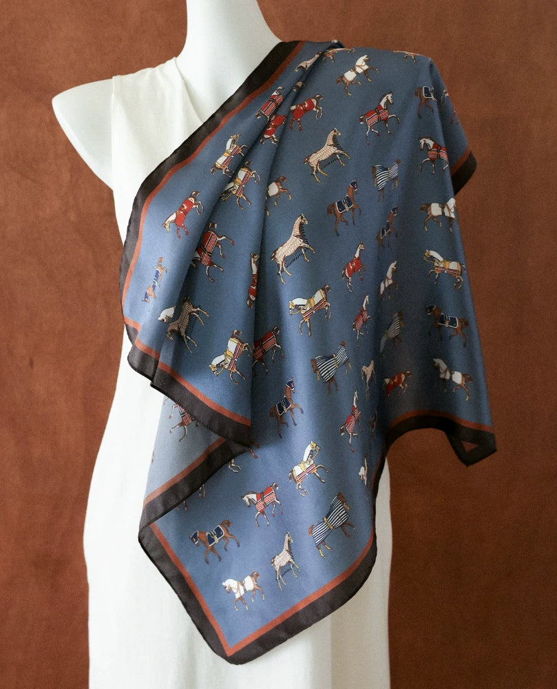 Vintage blue horse print mulberry silk square scarf draped over a mannequin shoulder