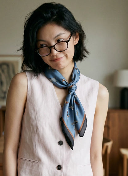 Woman wearing a vintage blue equestrian silk neckerchief with a sleeveless neutral outfit