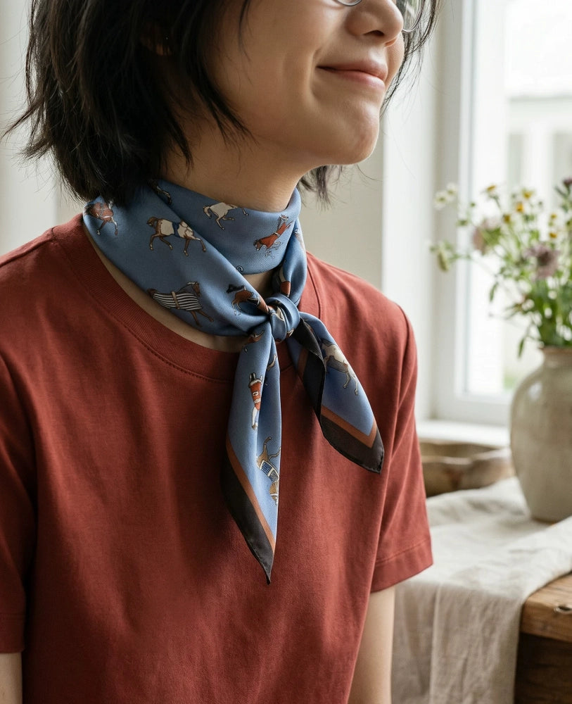 Vintage blue horse print silk scarf tied at the neck with a rust-colored top
