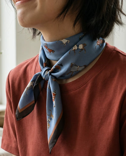 Woman wearing a vintage blue equestrian silk scarf in a relaxed layered neck style
