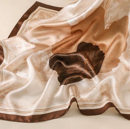 Close-up of a brown floral mulberry silk scarf showing its lustrous crepe satin texture