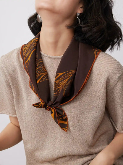 Vintage brown goldfinch silk scarf tied at the neck, adding a refined accent to a soft knit outfit.
