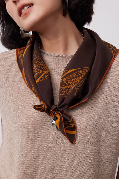 Close-up of brown 100% mulberry silk square scarf tied around the neck with elegant gold and paisley details.