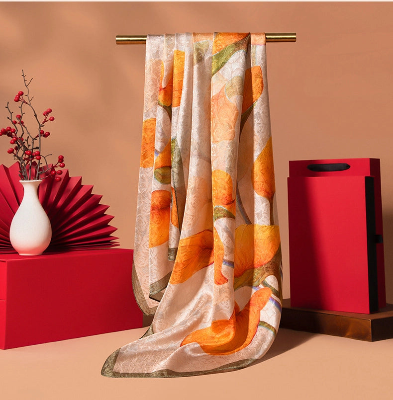Warm orange printed silk long scarf with floral design, soft mulberry silk feel, and graceful styling.