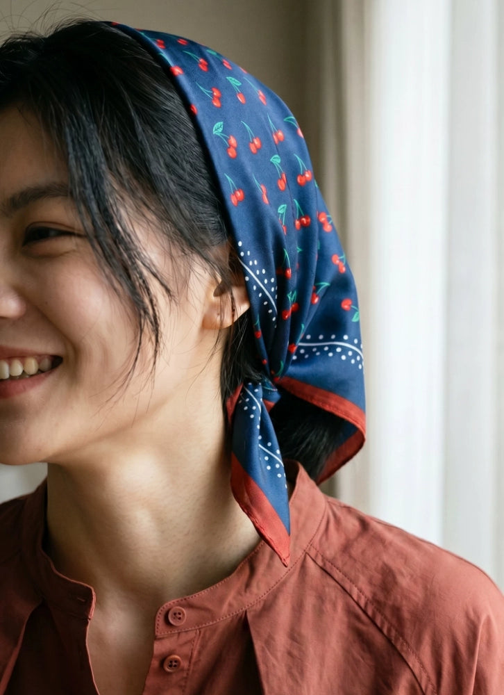 Model wearing a navy cherry print mulberry silk scarf as a retro headscarf
