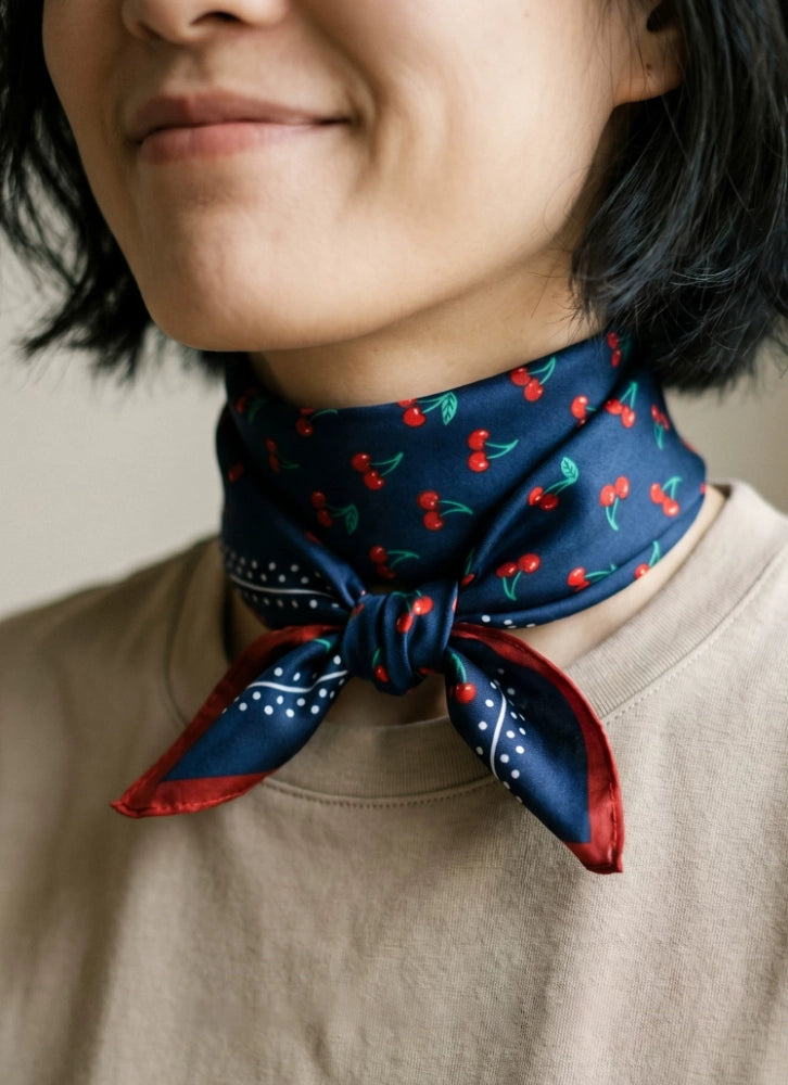 Navy cherry mulberry silk neck scarf wrapped closely around the neck with a beige top