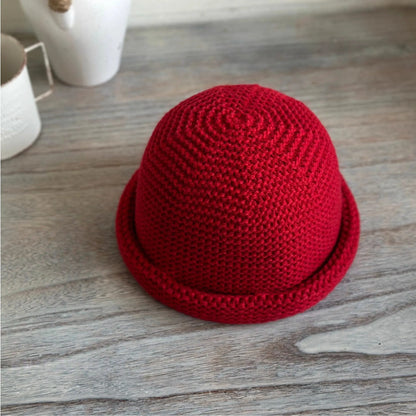 Top-front view of a vintage red wool blend knit hat showing spiral crown stitching and rolled edge