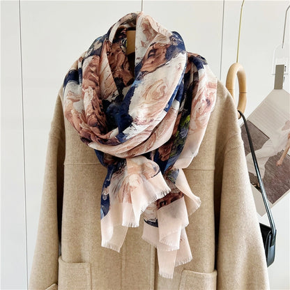 Oversized floral wool scarf wrapped in a soft layered cowl around the neckline of a beige coat