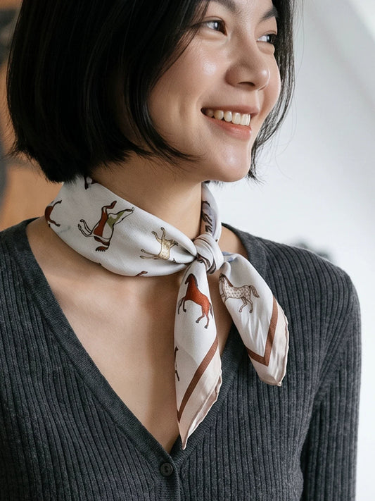 Close-up of a vintage white horse print silk scarf tied in an elegant side knot