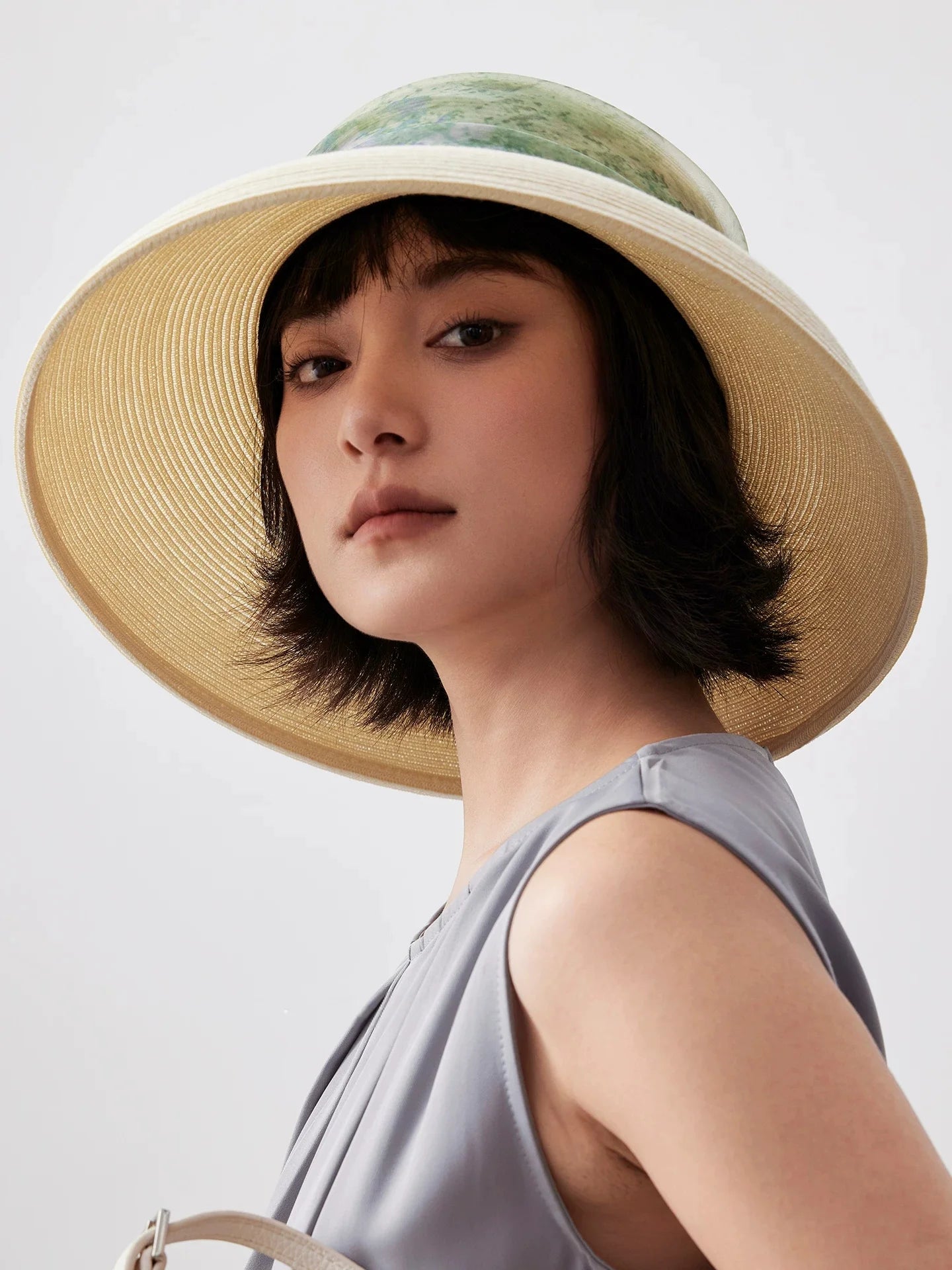 Woman wearing vintage white scarf ribbon wide brim sun hat with gray summer dress.