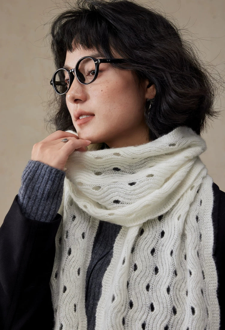 Close-up of a cream white cashmere scarf wrapped around the neck, highlighting its wave pointelle knit.