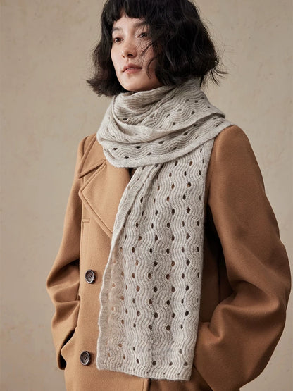 Light khaki cashmere scarf wrapped around the neck, with a long end hanging down the front of a camel coat.