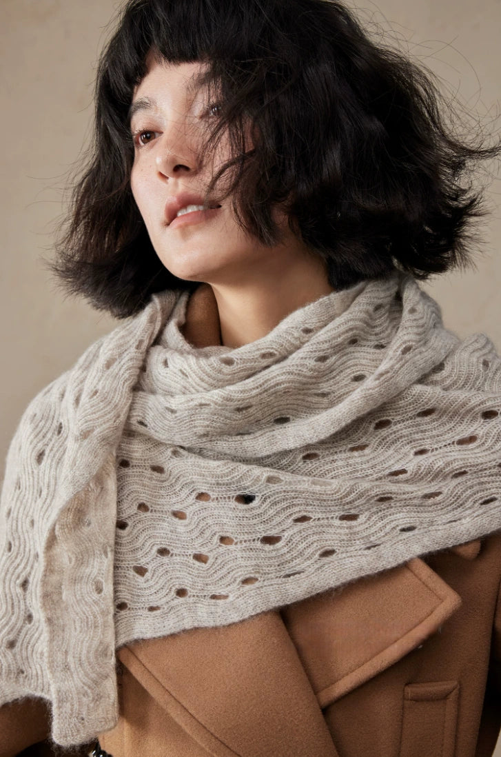 Angled view of a light khaki cashmere scarf draped across the shoulders, showing its openwork wave pattern.