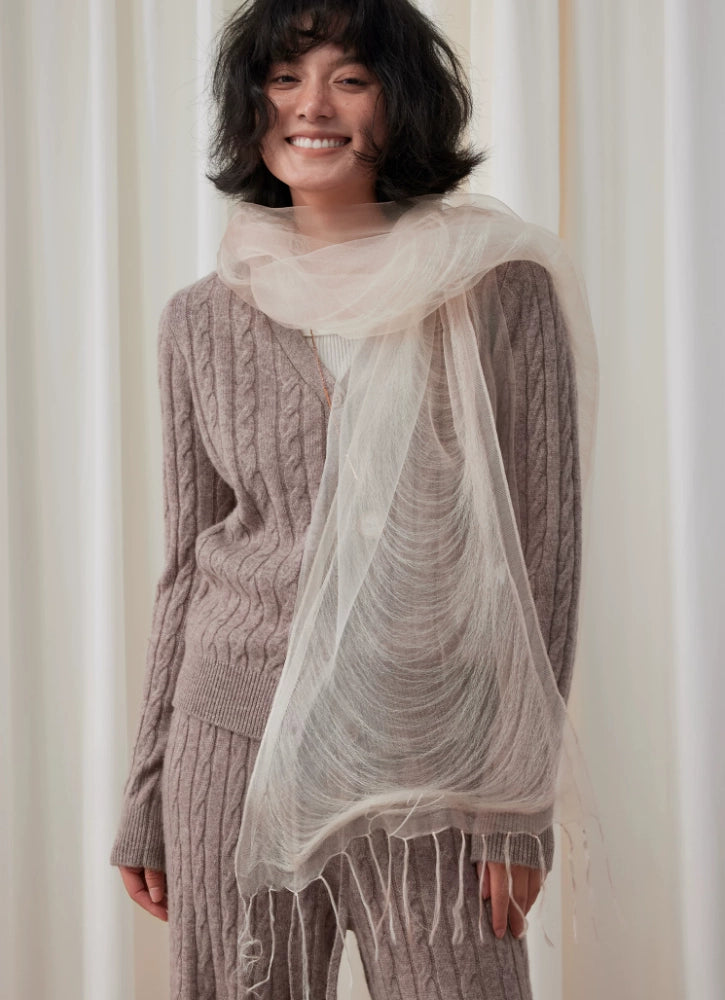 Woman wearing a lightweight wheat white silk scarf over neutral knitwear