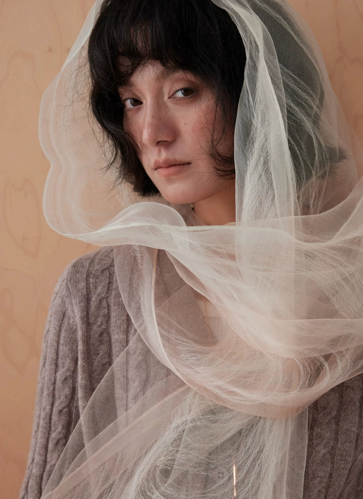 Close-up of a sheer wheat white silk scarf draped over the head and shoulders