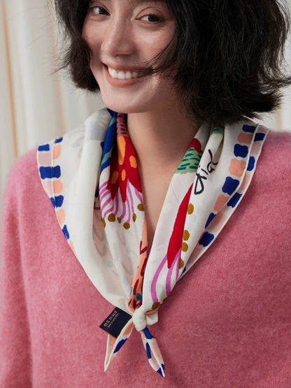 Close-up of an illustrated bird silk square scarf styled as a pointed neckerchief
