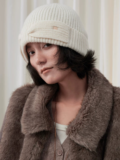 Close-up of a model wearing a white wool bow beanie, showing the bow across the folded cuff.
