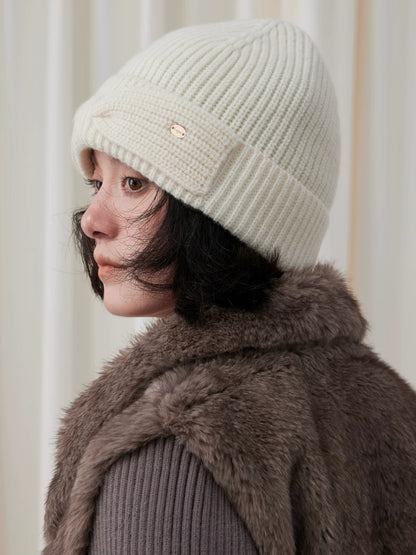 Side view of a white wool bow beanie on a model, showing the ribbed crown and folded cuff.