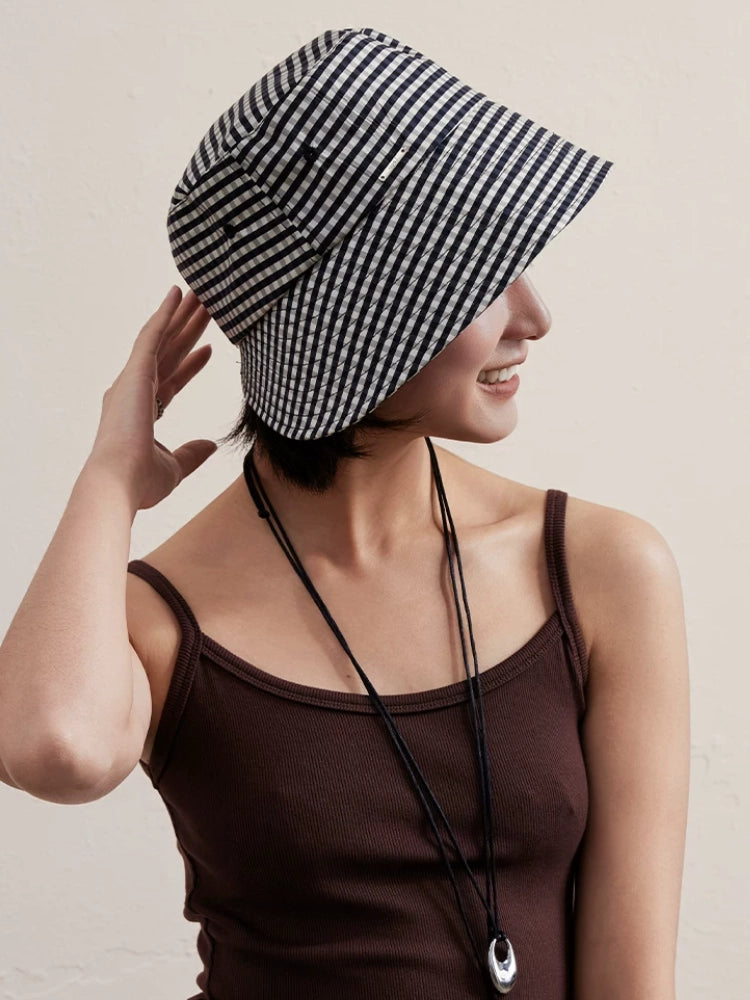 Woman wearing a black and white plaid wide brim bucket hat in casual summer style