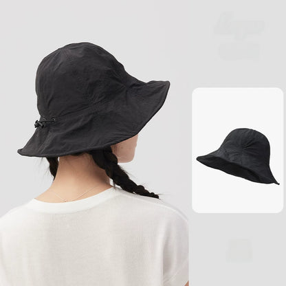 Rear view of a woman wearing a black wide brim bucket hat with an adjustable drawstring.