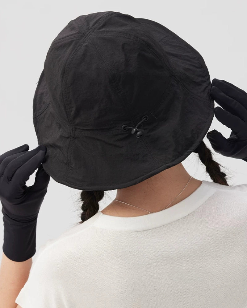 Close-up rear view of a black bucket hat showing crown seams and a wide brim held with both hands.