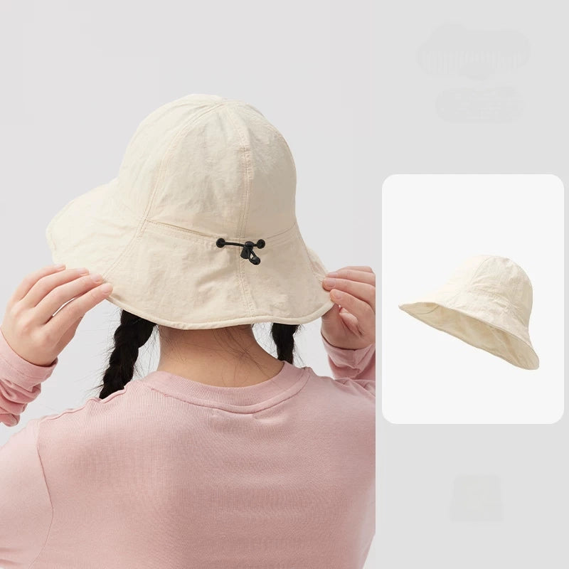 Rear view of a woman wearing an ivory wide brim bucket hat, showing the black drawstring adjuster.