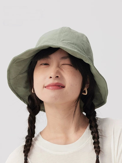 Front view of a woman wearing a sage green bucket hat, showing the wide brim and rounded crown.