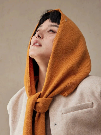 Close-up of woman wearing a burnt orange wool hooded scarf tied at the neck