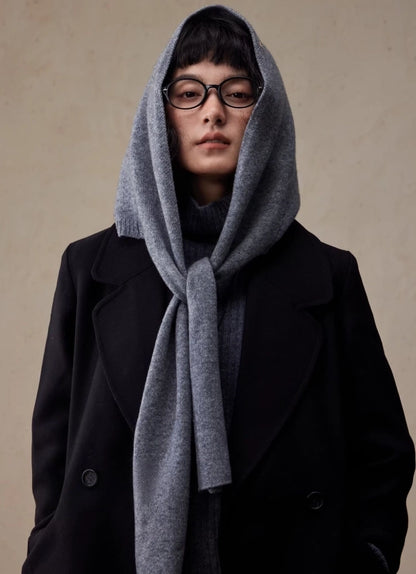 Woman wearing a dark grey wool hooded scarf tied at the neck over a black coat