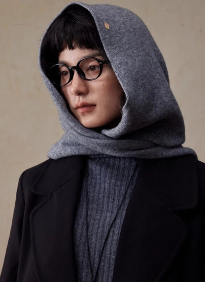 Side view of woman wearing a dark grey wool hooded scarf over a knit sweater and black coat