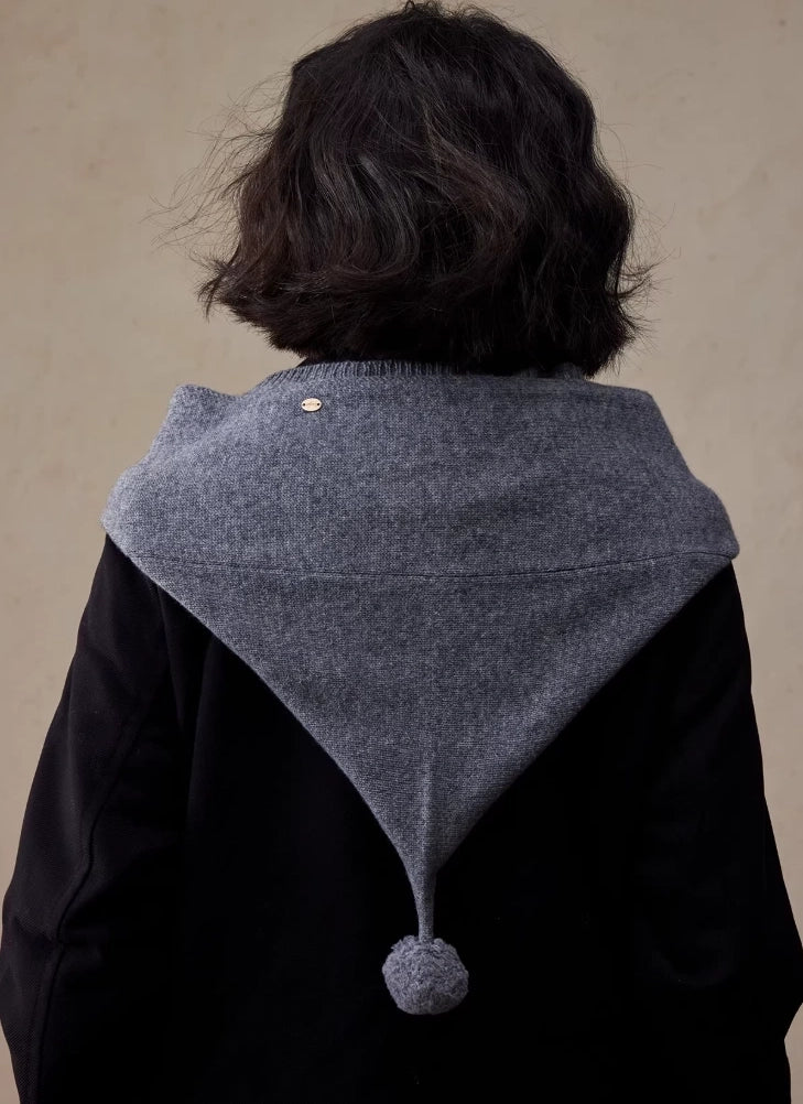 Back view of dark grey wool hooded scarf draped over the shoulders with pom pom detail
