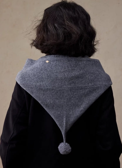 Back view of dark grey wool hooded scarf draped over the shoulders with pom pom detail