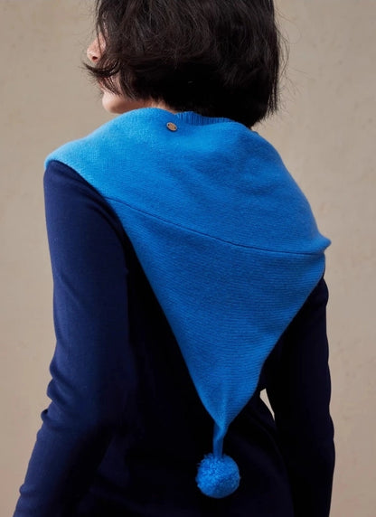 Back view of royal blue wool hooded scarf with pointed drape and pom pom detail