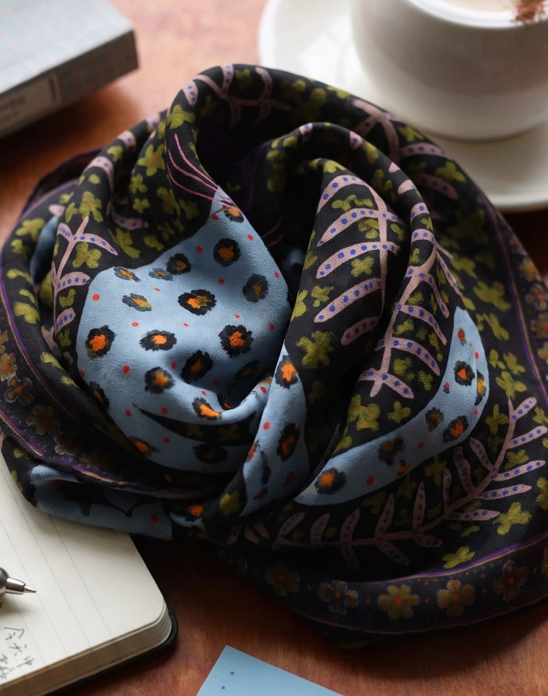 Folded woodland brown leopard silk scarf showing a pale blue spotted cat and botanical border