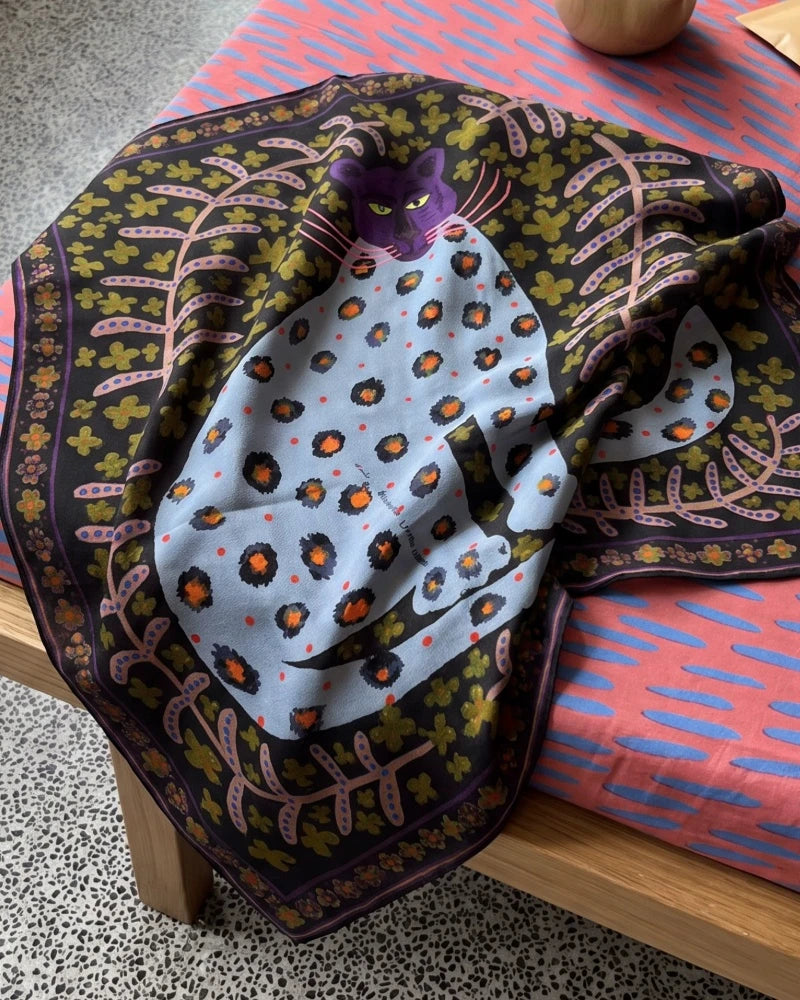 Close-up of a woodland brown and plum silk square scarf with leopard and floral artwork