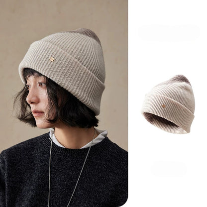 Beige taupe wool color block beanie shown on a model and as a standalone hat, with a ribbed cuff and diagonal contrast.